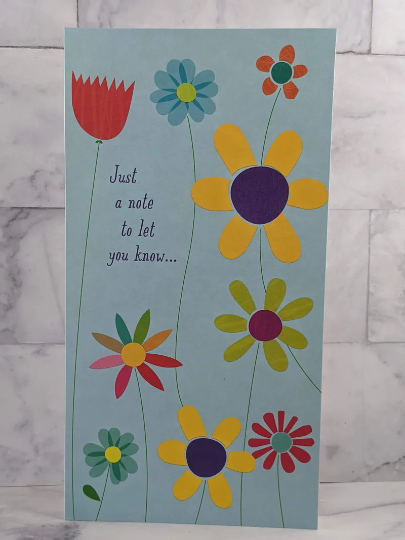 A Hallmark thinking-of-you greeting card with a blue cover that has a design of colorful flowers.