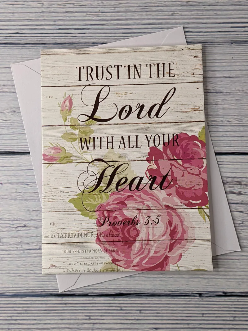 A Proverbs 3:5 Bible verse notecard that is blank inside, with a design on the cover of pink flowers on a white-wood pattern.
