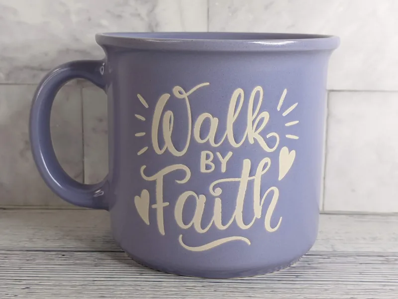 A lavender purple mug with the words "walk by faith" on both sides.