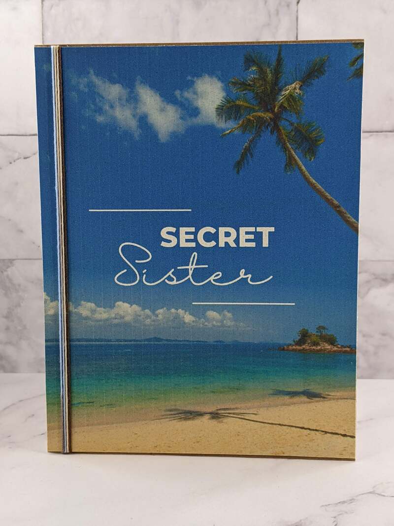 A Secret Sister greeting card with an image of a peaceful beach on the cover.