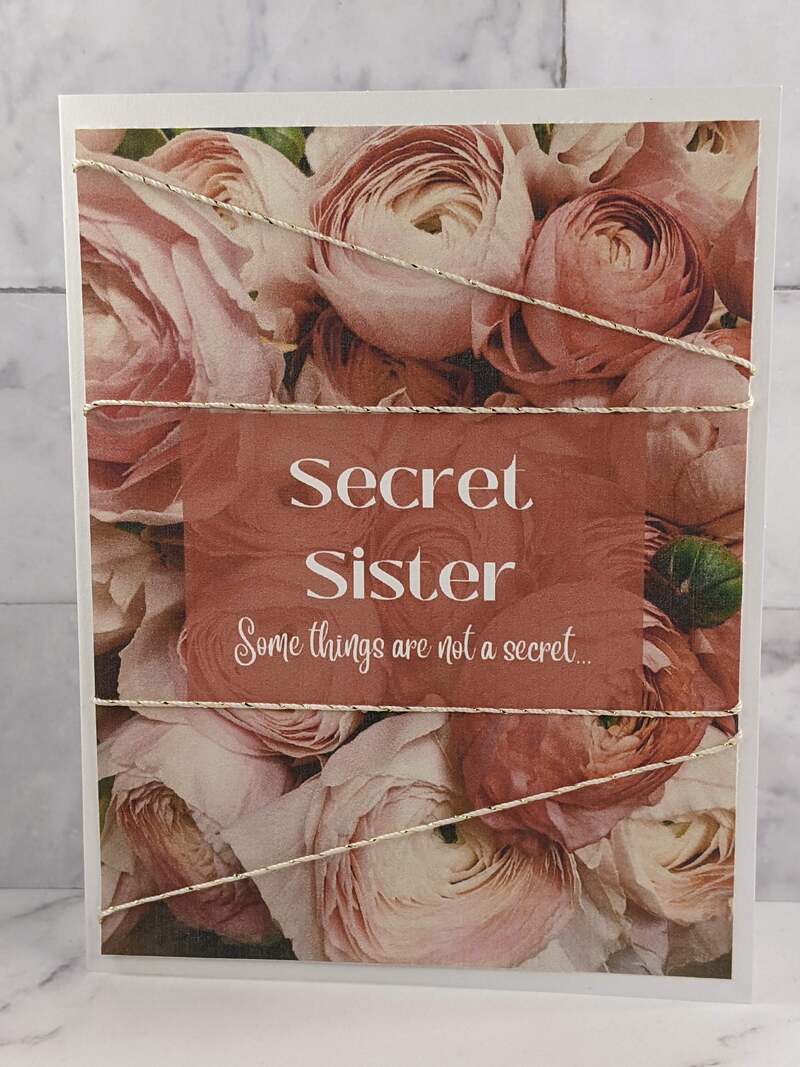 A greeting card for a Secret Sister with an image of pink flowers on the cover and a message of friendship.