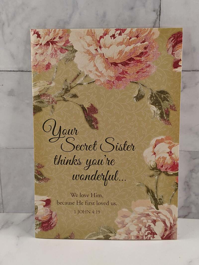 A Secret Sister greeting card with a tan cover, pink flower design, and a thinking-of-you message.
