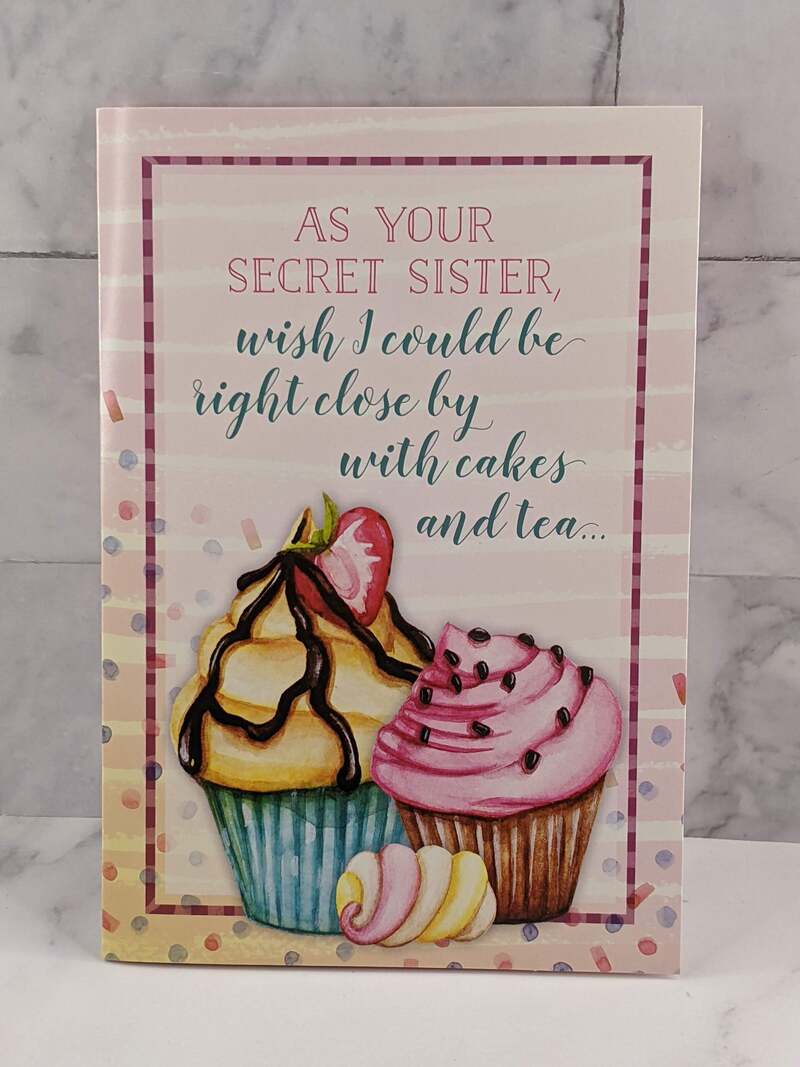 A pink greeting card with pink cover that has an image of cupcakes and a thinking of you message for a Secret Sister.