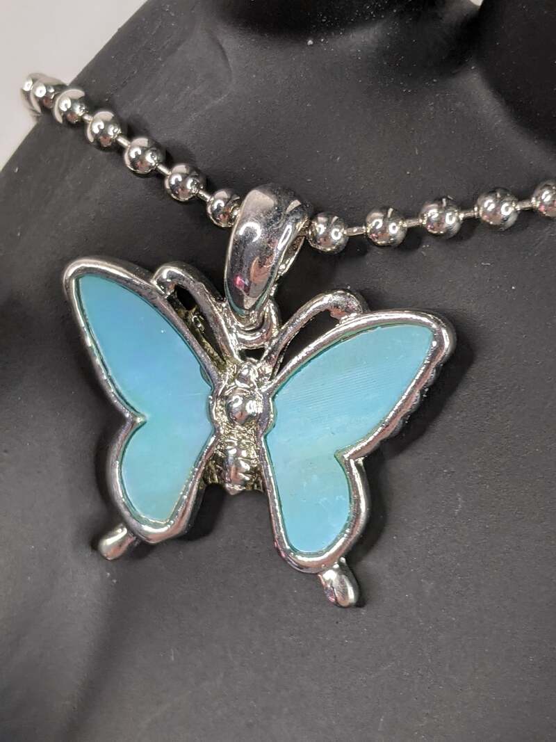 A blue Mother of Pearl pendant shaped like a butterfly on a silver ball-chain necklace.