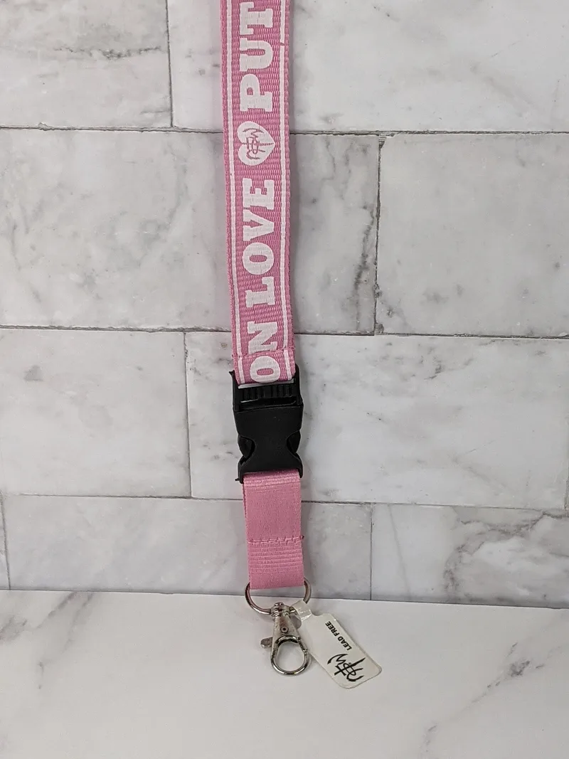 A pink lanyard with white lettering, featuring the words Put on Love.