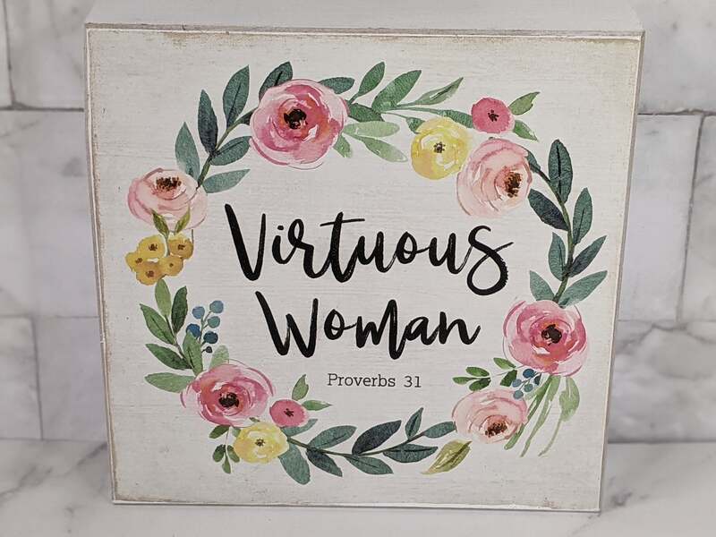 A white wooden sign with a pink floral design, featuring the words "Virtuous Woman - Proverbs 31"