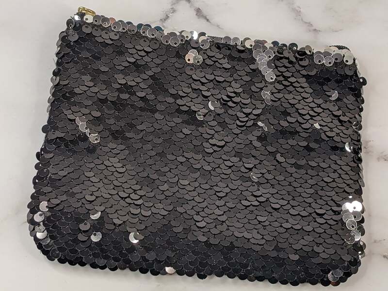 A small pouch with black sequins that are silver when flipped.