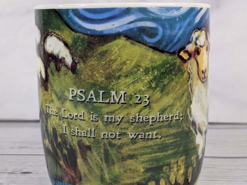 A Christian mug with sheep artwork in vivid colors, featuring a Psalm 23 Bible verse.