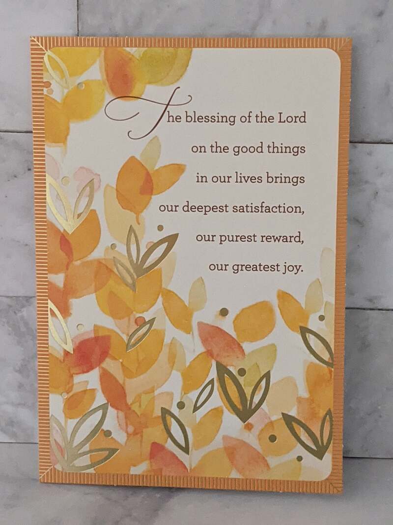 A Christian congratulations card with a Bible verse, and a design of orange, coral, and gold leaves on the cover.