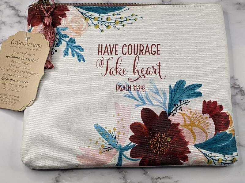 A canvas make-up or cosmetic pouch with a burgundy zipper closure, floral design and courage message.