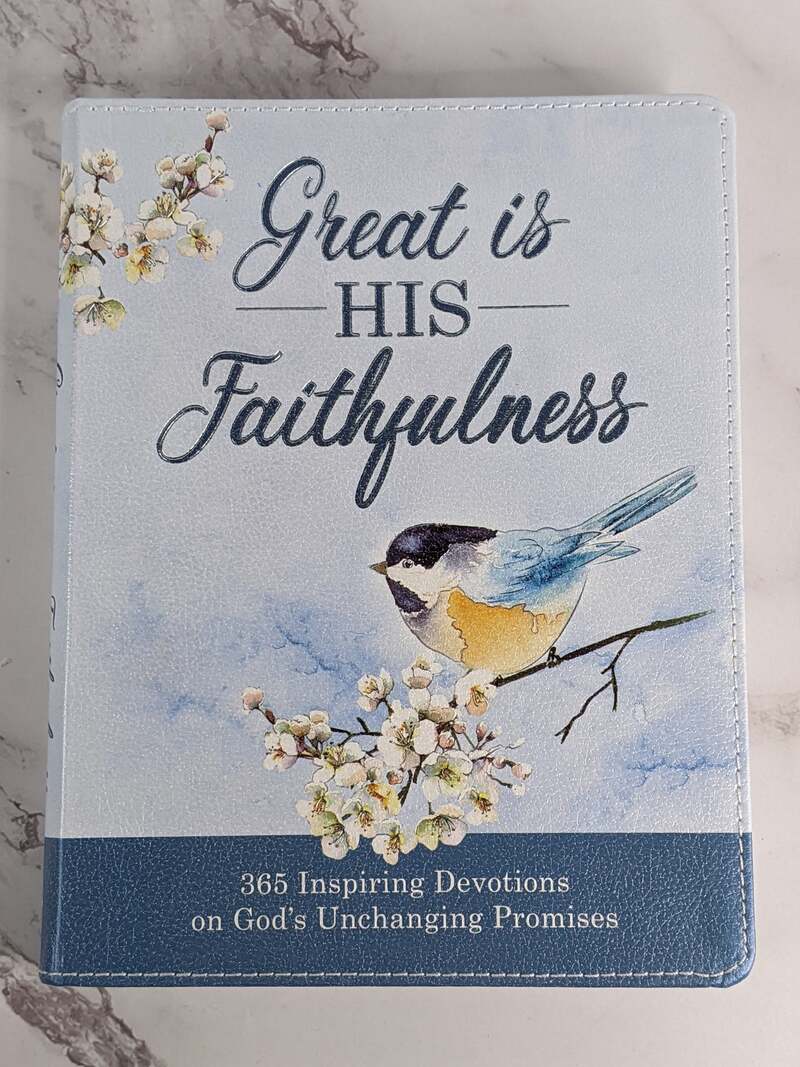 A leather-like light blue devotional book with a bird and flower design on the cover, that features religious devotions.