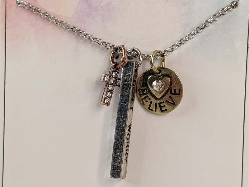 A religious silver necklace chain with three charm pendants featuring a cross and the words, "don't worry, instead pray."